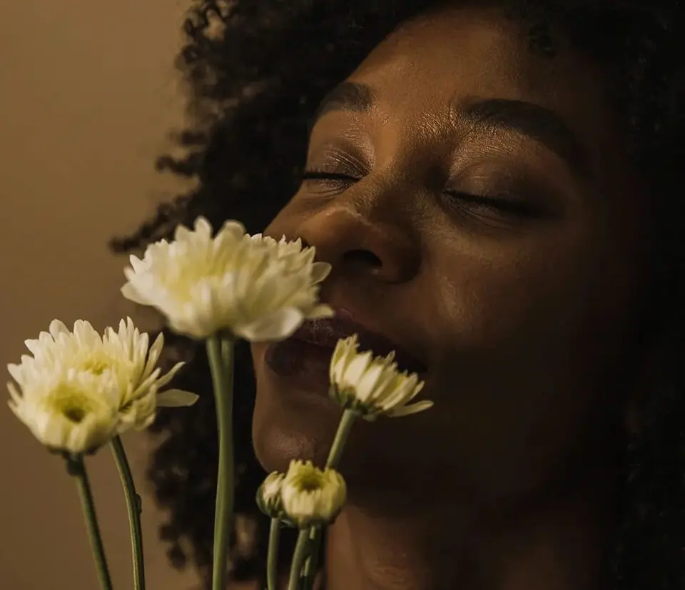 A woman with her eyes closed smelling flowers.